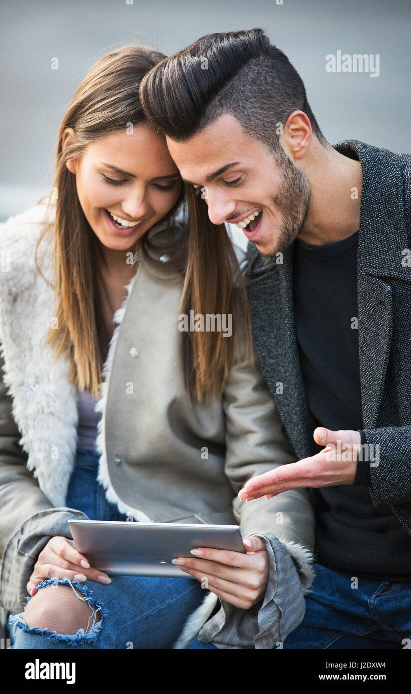 Portrait of beautiful smilling young couple using a digital tablet and ...