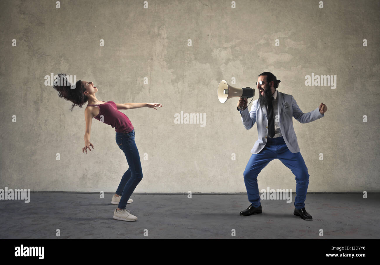 Bearded man with megaphone yelling at woman Stock Photo