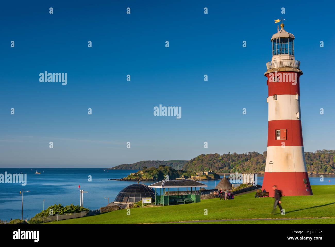 People enjoy the early morning sunshine near Smeatons Tower on Plymouth Hoe in south Devon. Stock Photo