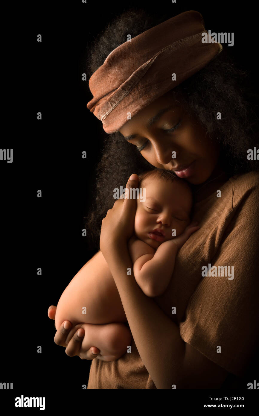 Ethiopian young mother holding her 7 days old little baby against a dark background Stock Photo