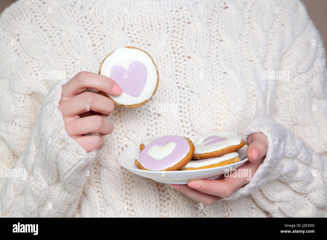 Closeup of woman with white sweater holding biscuit. Stock Photo