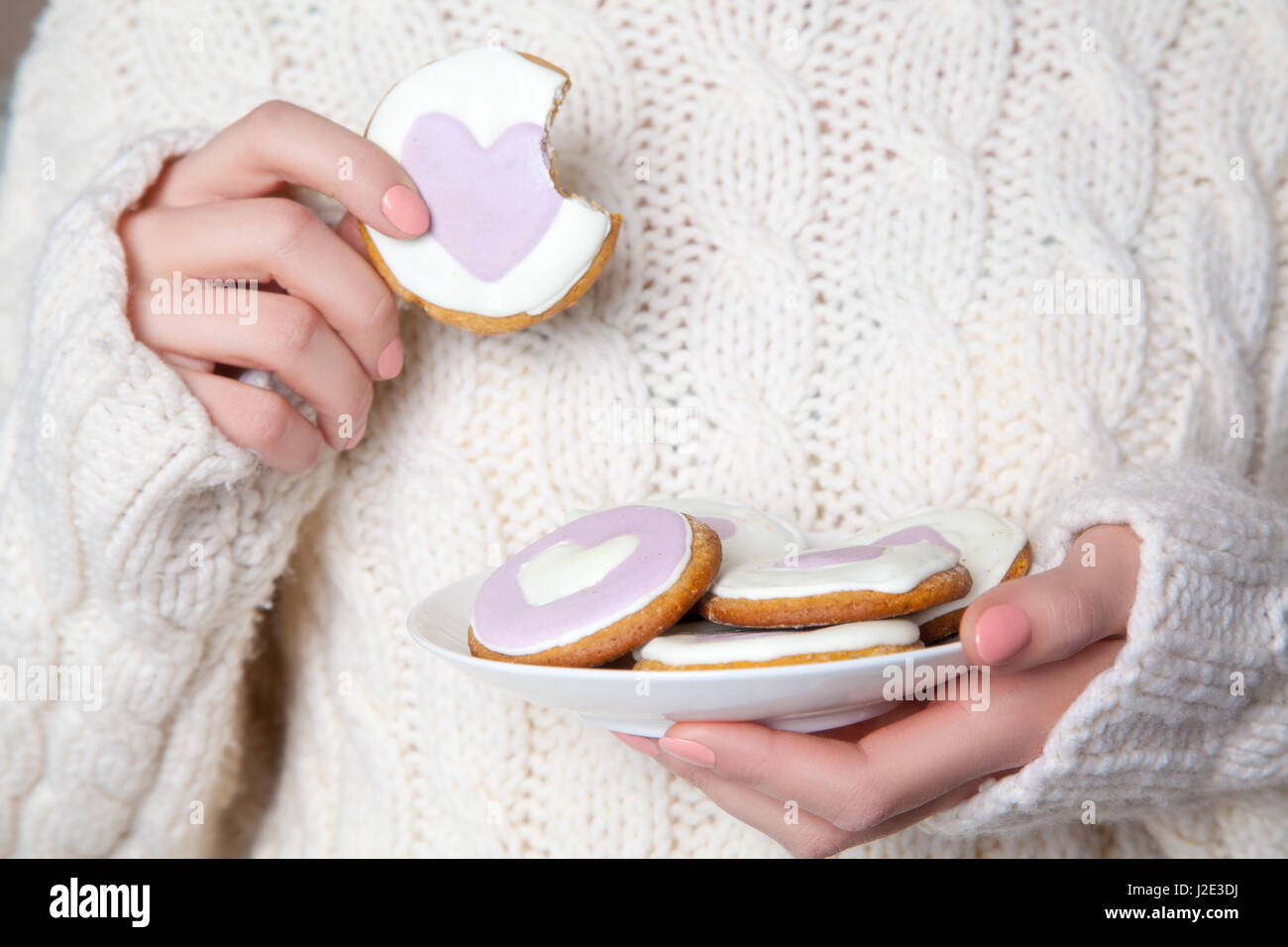Closeup of woman with white sweater holding biscuit. Stock Photo