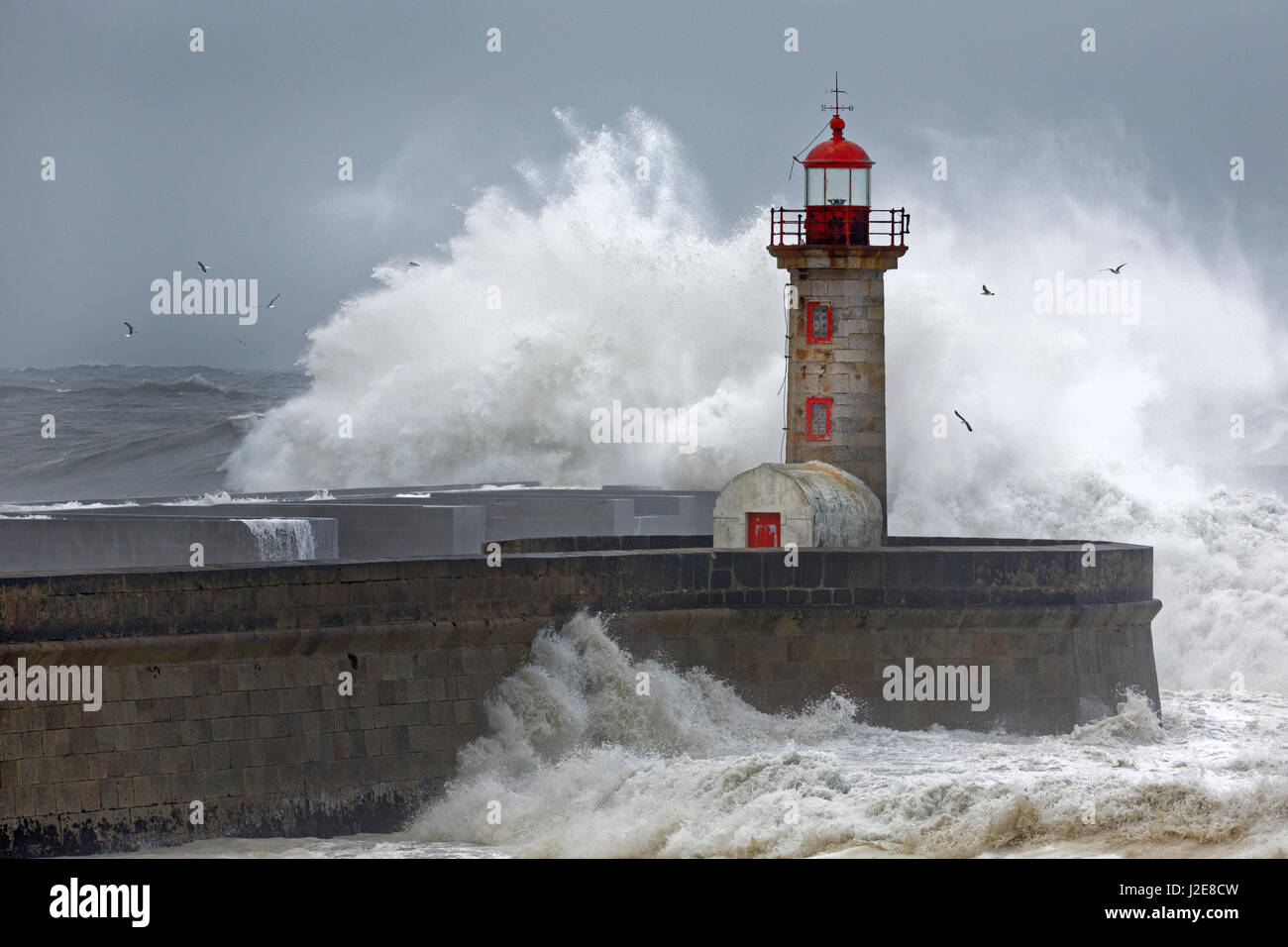High waves, splashing spray, lighthouse during storm, Porto, Portugal Stock Photo