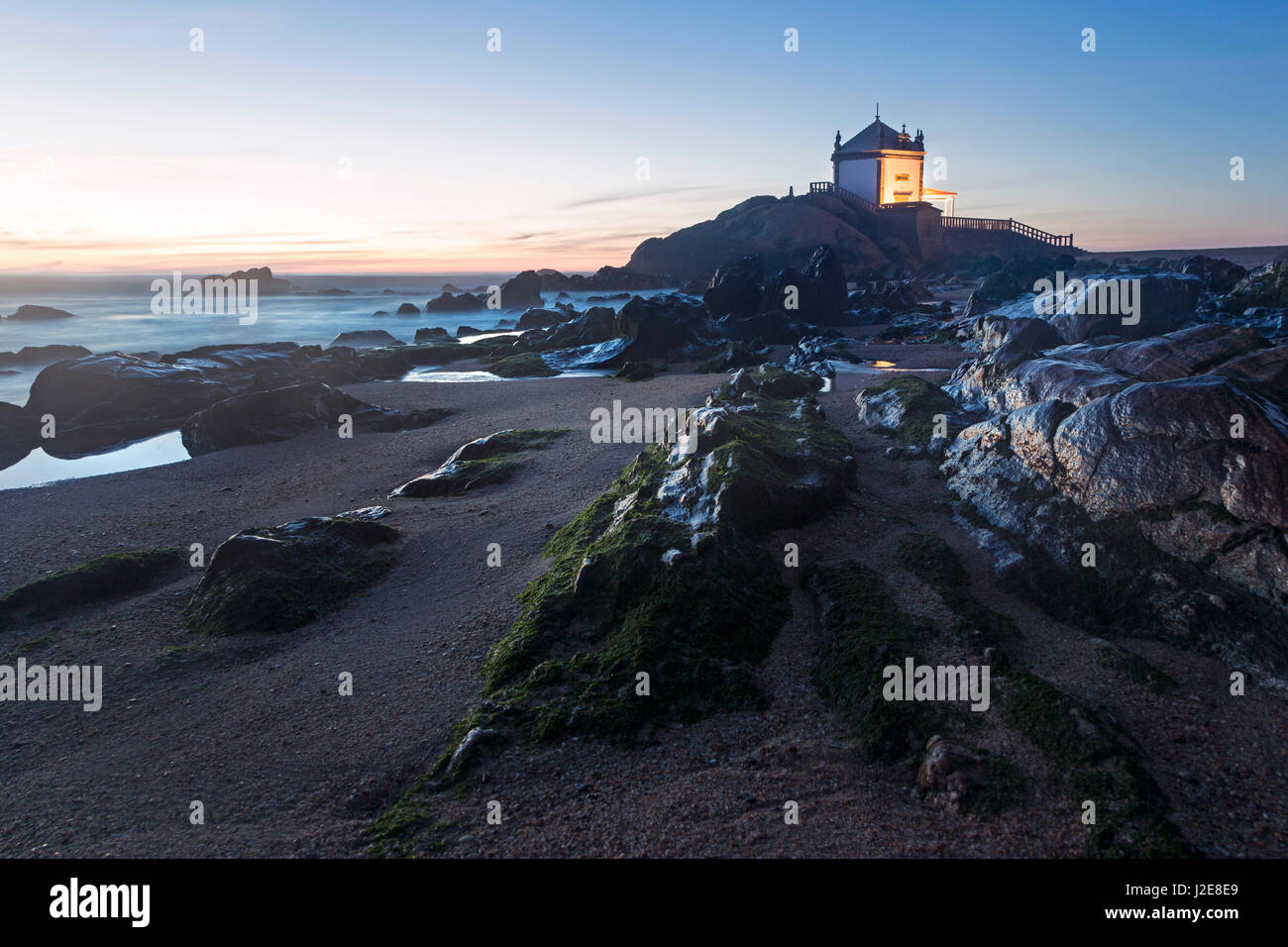 Capela do Senhor da Pedra, Chapel at dusk, rocky beach, Portugal Stock Photo