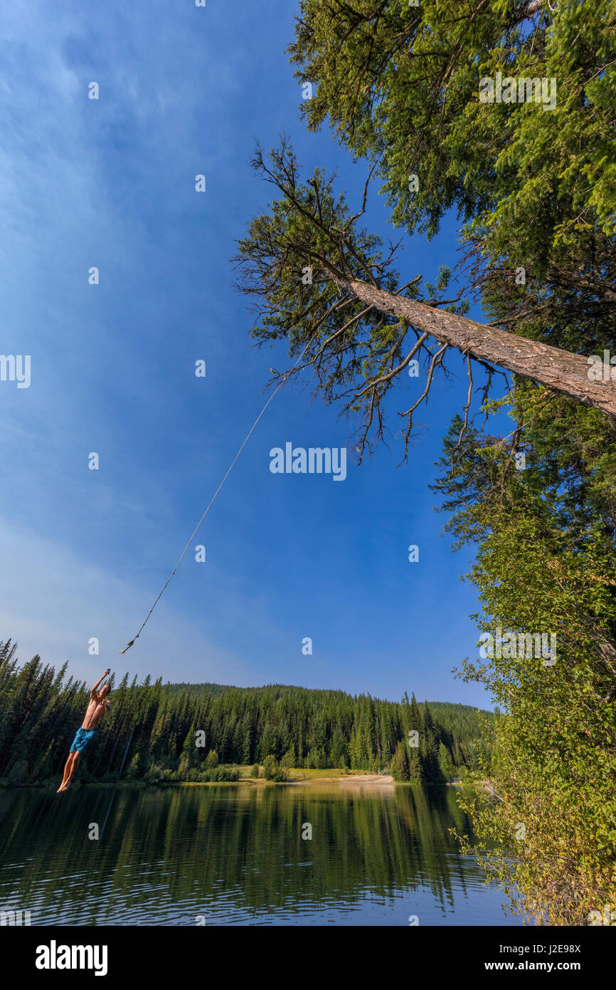 Jumping off a tree rope on a summer day at Champion Lakes Provincial Park, British Columbia, Canada, (MR) Stock Photo