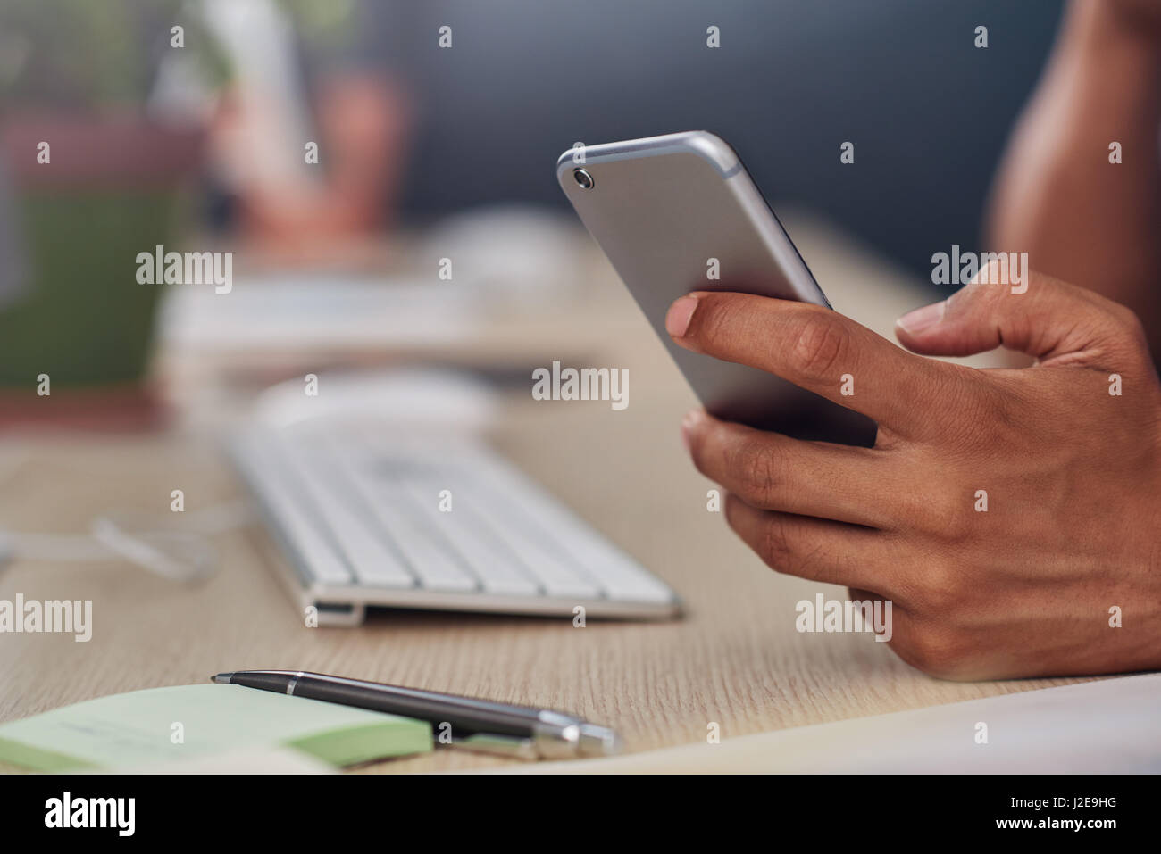 Young designer using a cellphone at his office desk Stock Photo
