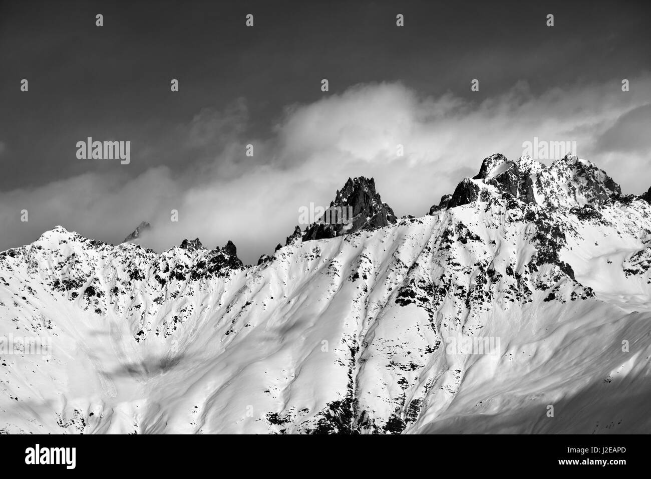 Black and white snow avalanches mountainside in clouds. View from ski lift on Hatsvali, Svaneti region of Georgia. Caucasus Mountains. Stock Photo