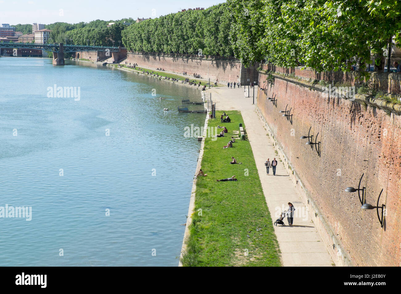 France, Toulouse, near the Pont Neuf bridge, Henri Martin promenade adjacent to the Garonne River, young couples share time together and individuals lie in the sun looking at their cell phones. Stock Photo