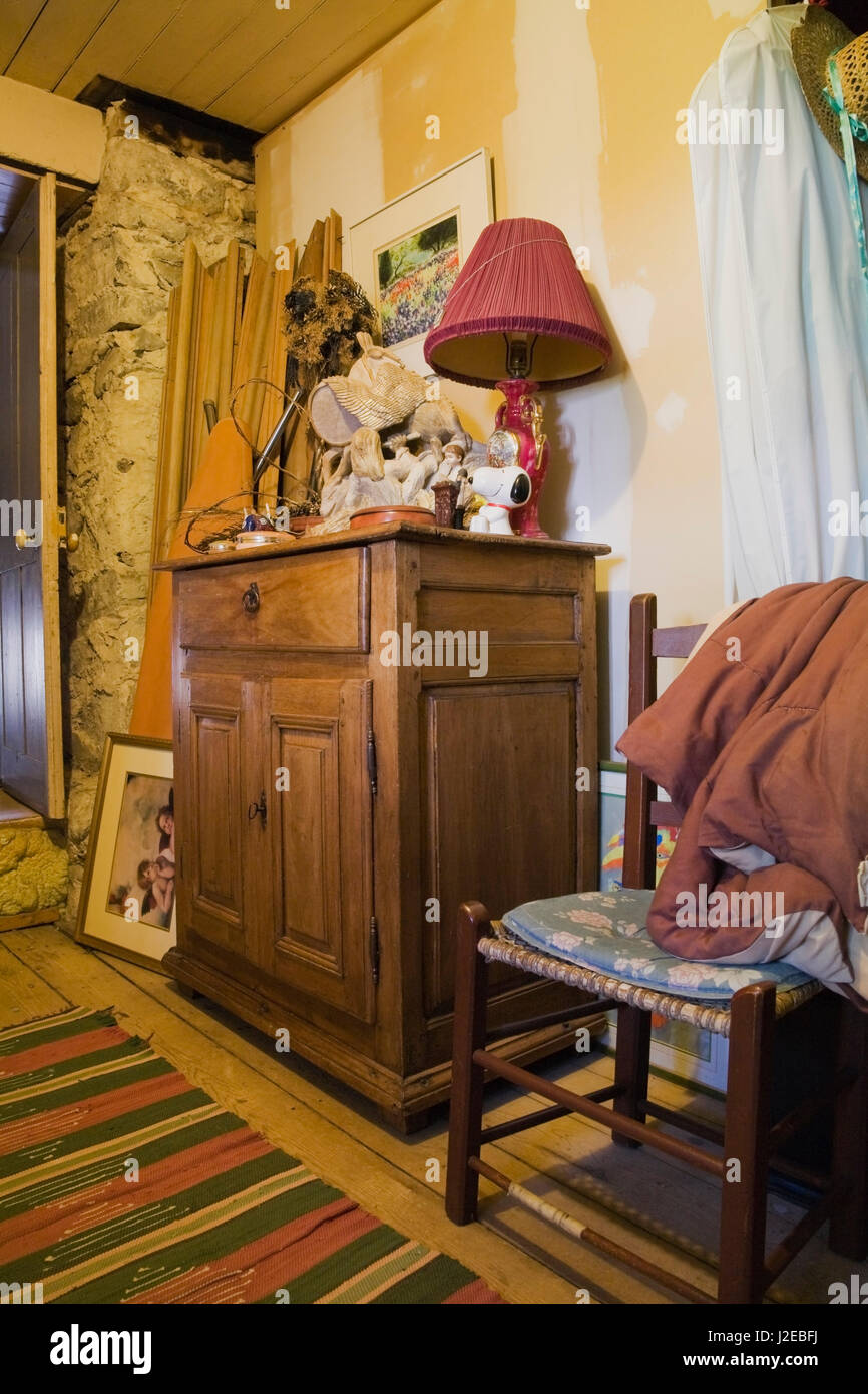 Baseboard moldings stacked upright, picture frames and dresser with red