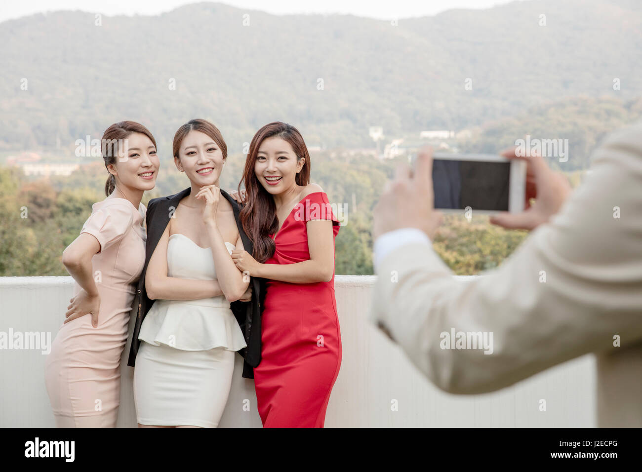 Three young smiling women posing for photos at party on rooftop Stock Photo