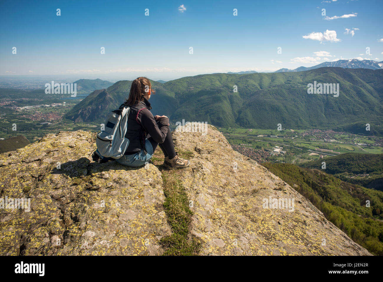 Woman with Backpack Sitting on Top of Mountain with Panoramic View, Mocchie, Piedmont, Italy Stock Photo