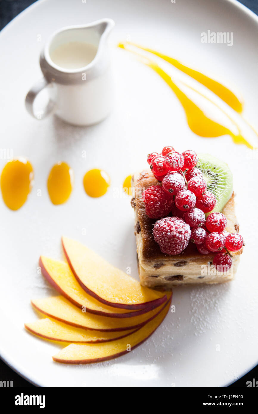 Bread and butter pudding with red berries and coulis and a jug of cream