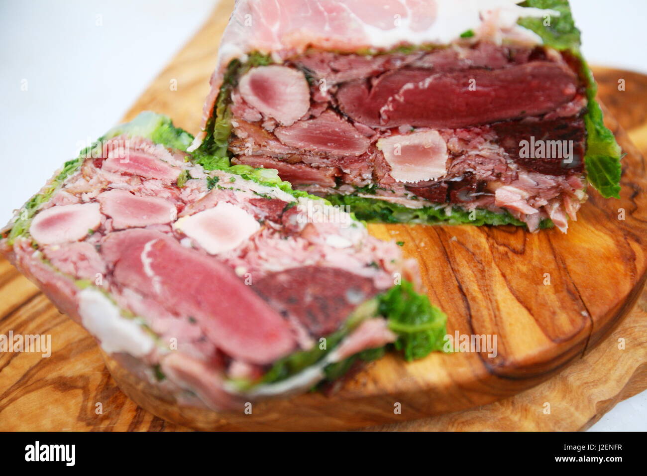 A meat terrine with one slice bit on a wooden board Stock Photo