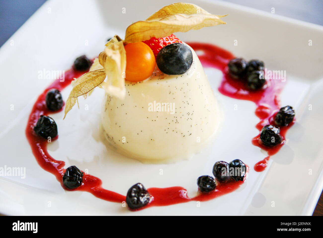 Panna cotta with blackcurrant coulis on a white plate Stock Photo