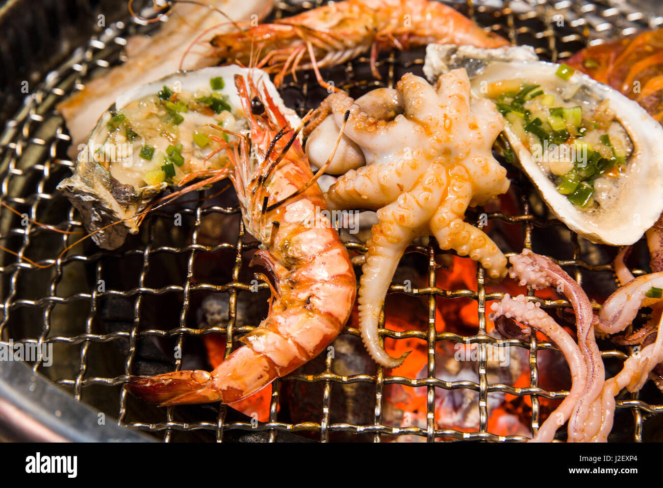 Grilling seafood of shrimp, octopus and oysters on hot charcoal Stock Photo