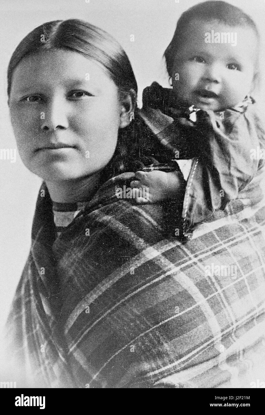 Historic Black and White of a Native American family of Cheyenne mother carrying her baby in a shawl on her back. Stock Photo