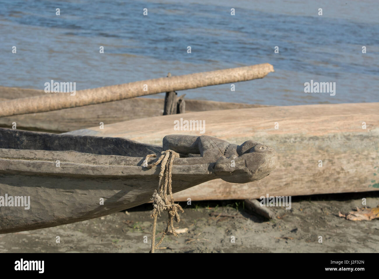 Melanesia, Papua New Guinea, Sepik River area, Village of Kopar. Traditional dugout canoe with carved bow along the riverbank. Stock Photo