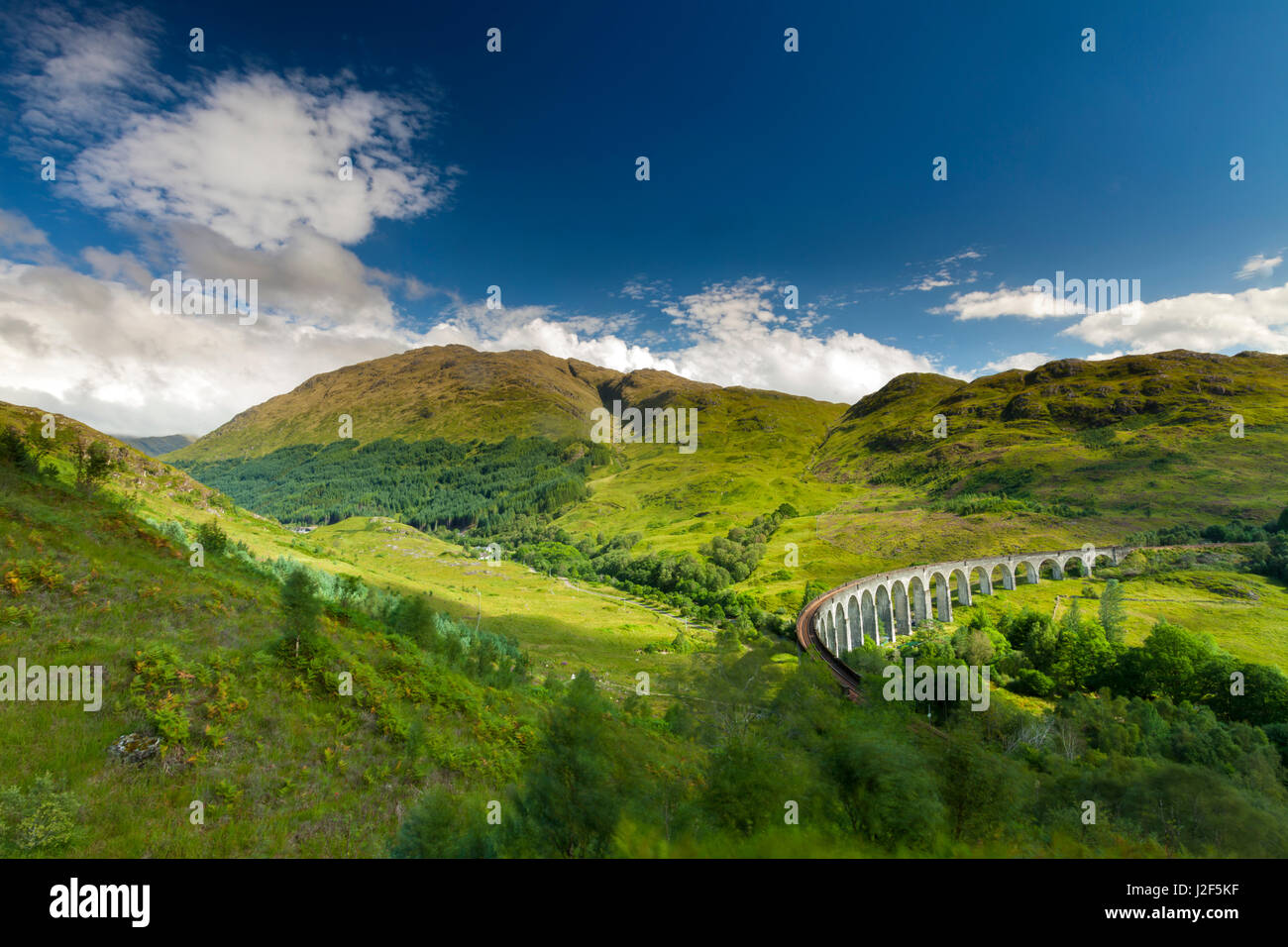 The Glenfinnan Viaduct, built in 1898, is built as single-track railway bridge over the valley and river. The big turn is necessary to lead the train from one hill to another hill The bridge has been used in various films including Harry Potter. Stock Photo