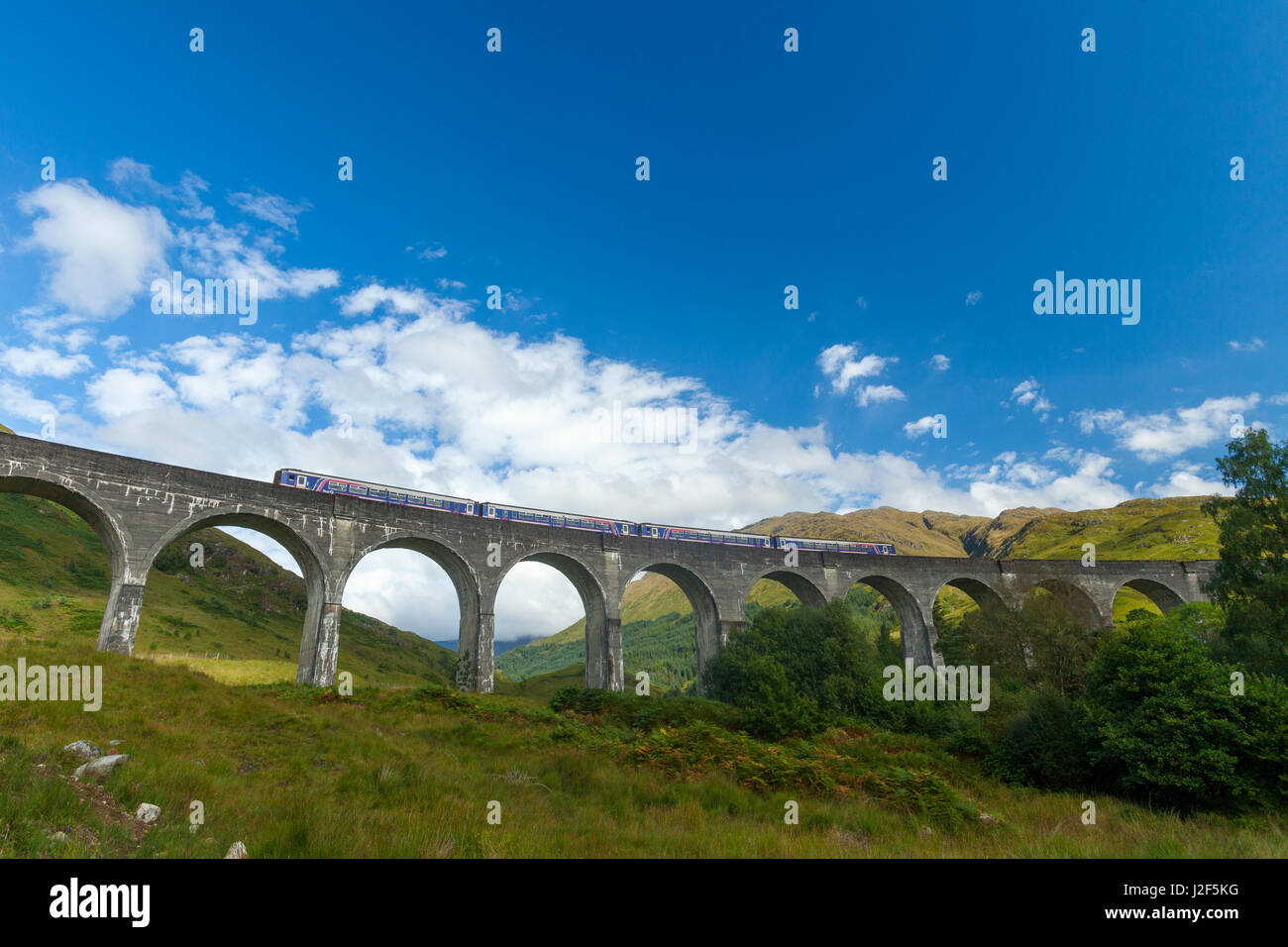 The Glenfinnan Viaduct, built in 1898, is built as single-track railway bridge over the valley and river. The big turn is necessary to lead the train from one hill to another hill The bridge has been used in various films including Harry Potter. Stock Photo