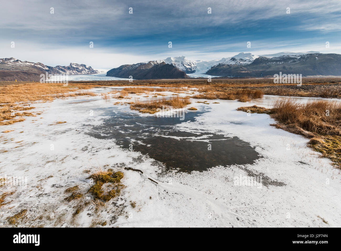 Winter landscape with frozen lake and tongues of the VatnajÃ¶kul glacier in the back Stock Photo