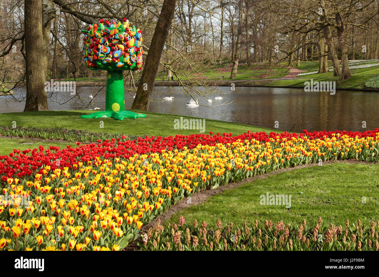 Garden architecture of the Keukenhof. Borders with colorful tulips and crocuses, a sculpture and a pond. Stock Photo