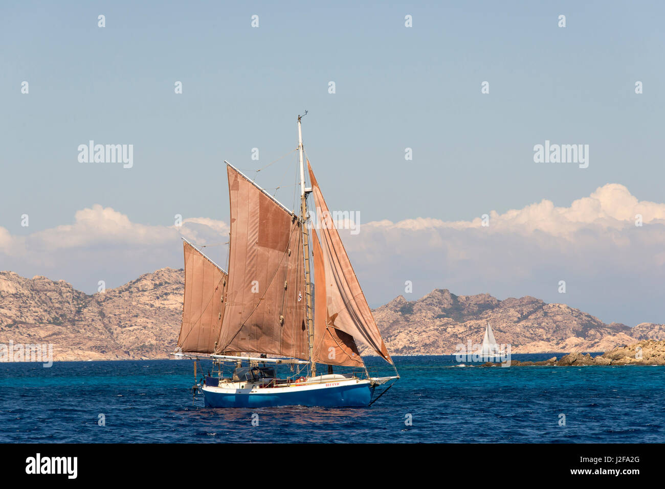 Italy, Sardinia. Red sails on gaff rigged sailboat Stock Photo