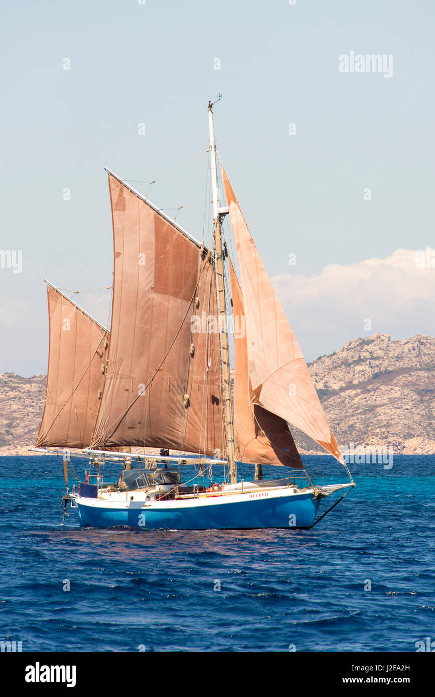 Italy, Sardinia. Colorful red sails on gaff rigged sailboat Stock Photo
