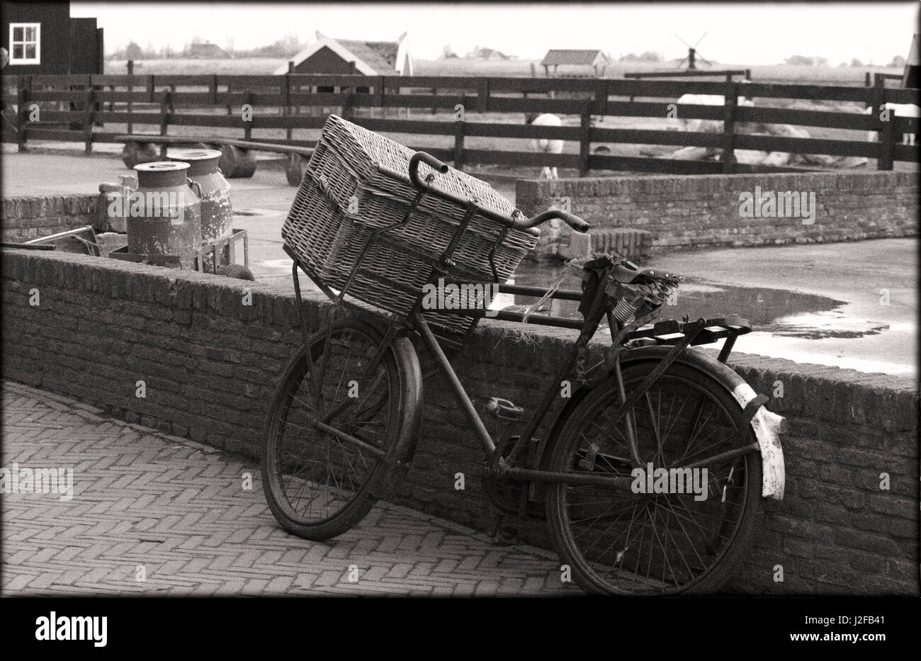 An old fashioned bike with basket leaning again brick wall on an old farm Stock Photo