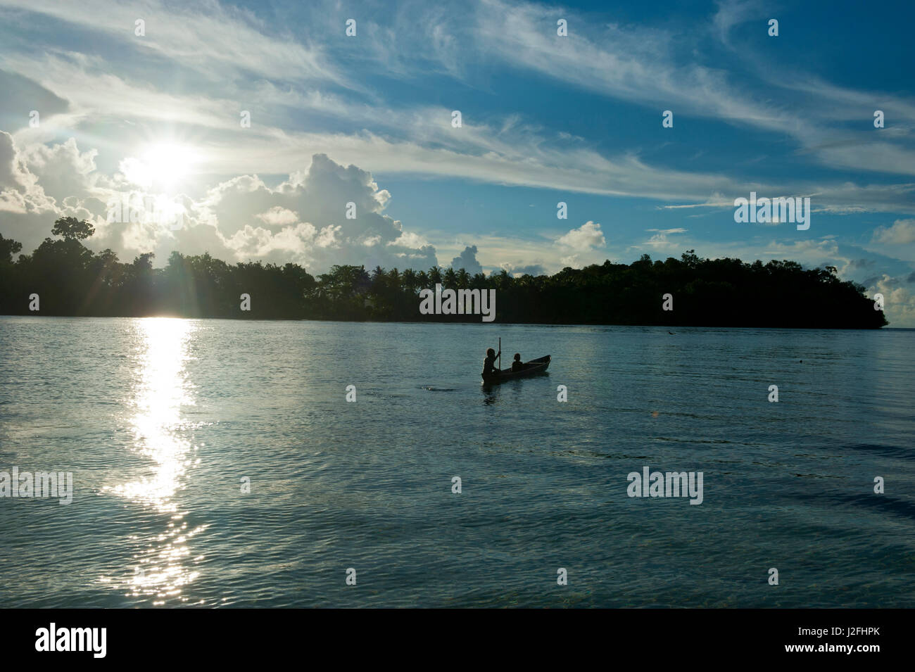 Boys in a canoe in backlight in the Marovo Lagoon, Solomon Islands, Pacific Stock Photo