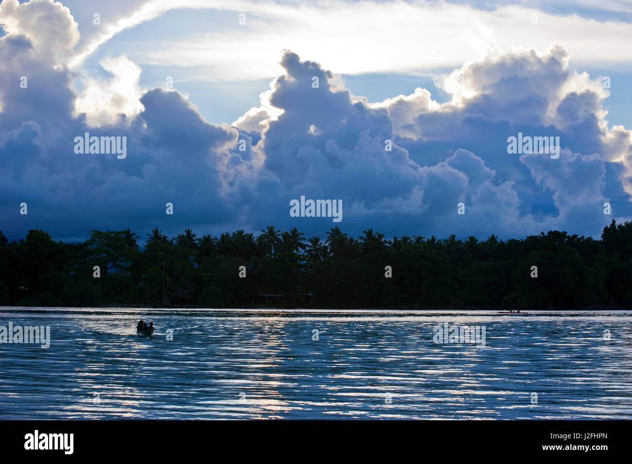 Boys in a canoe in backlight in the Marovo Lagoon, Solomon Islands, Pacific Stock Photo