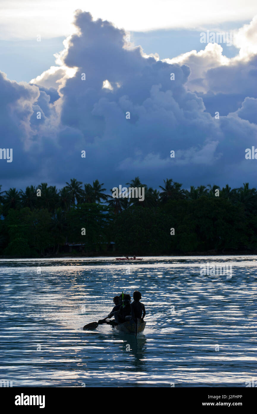 Boys in a canoe in backlight in the Marovo Lagoon, Solomon Islands, Pacific Stock Photo
