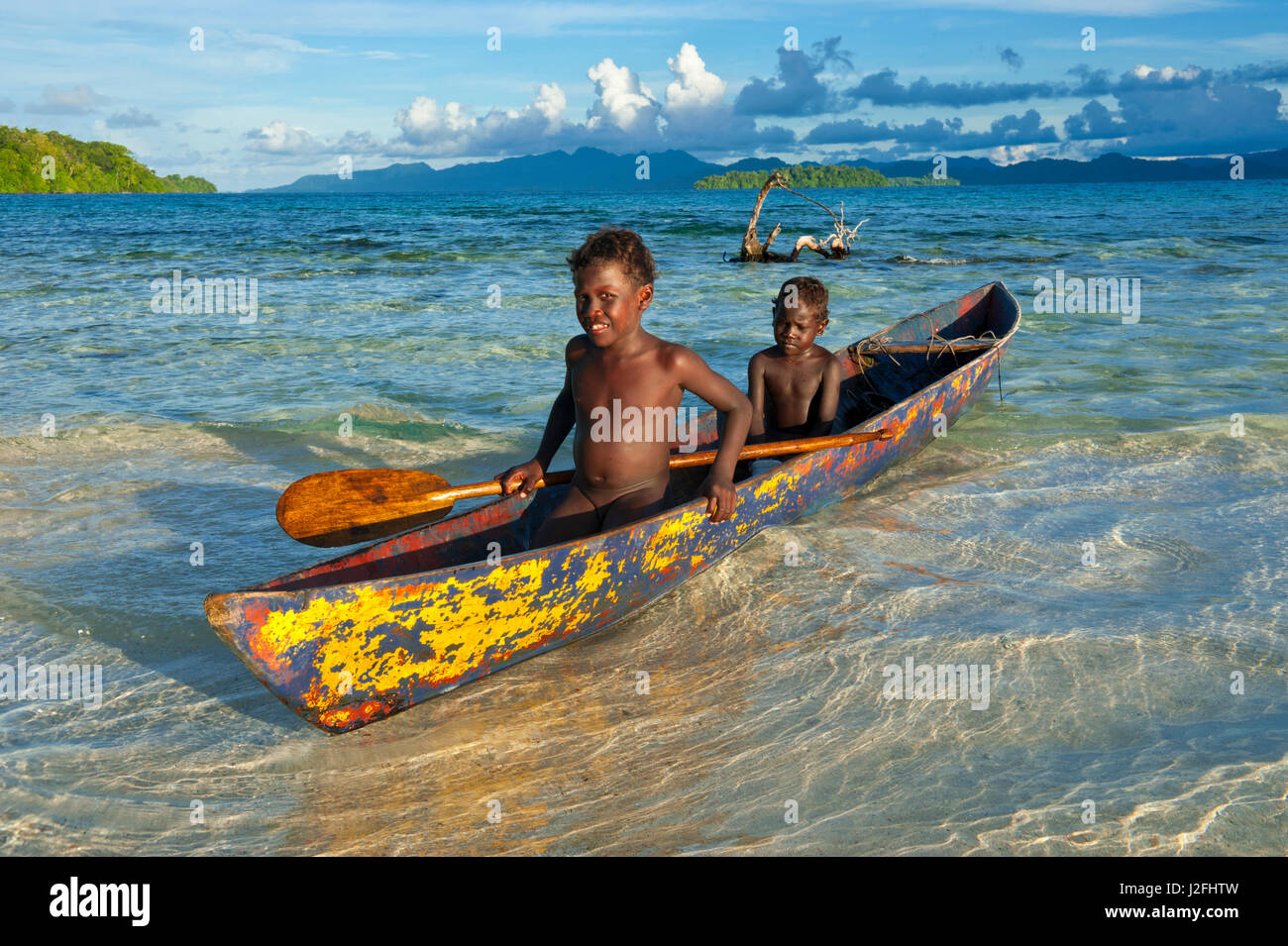 Young boys fishing in the Marovo Lagoon before dramatic clouds, Solomon Islands, Pacific Stock Photo