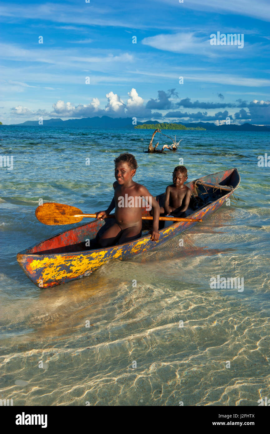 Young boys fishing in the Marovo Lagoon before dramatic clouds, Solomon Islands, Pacific Stock Photo