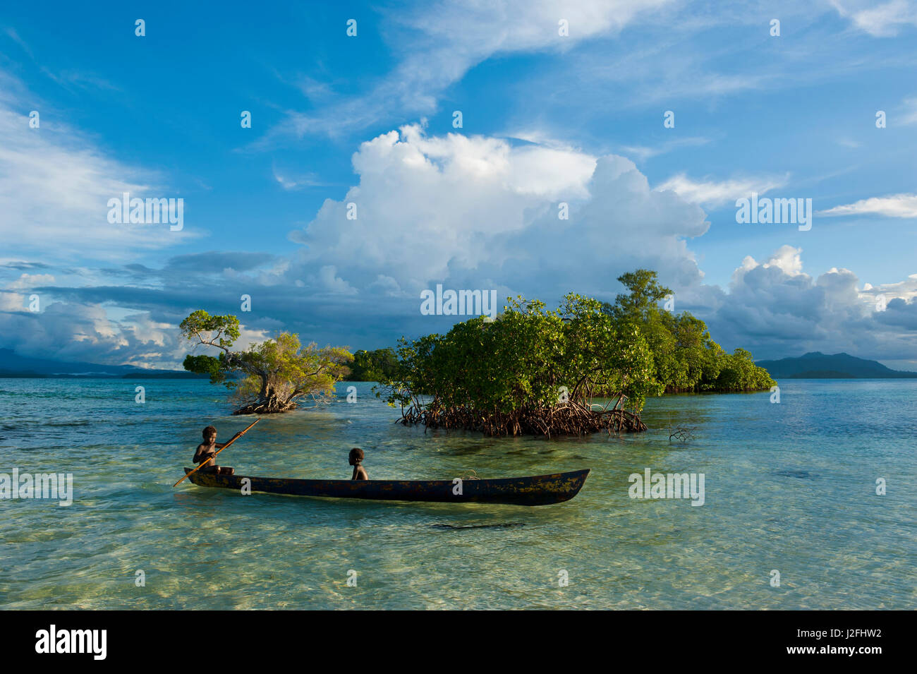 Young boys fishing in the Marovo Lagoon before dramatic clouds, Solomon Islands, Pacific Stock Photo