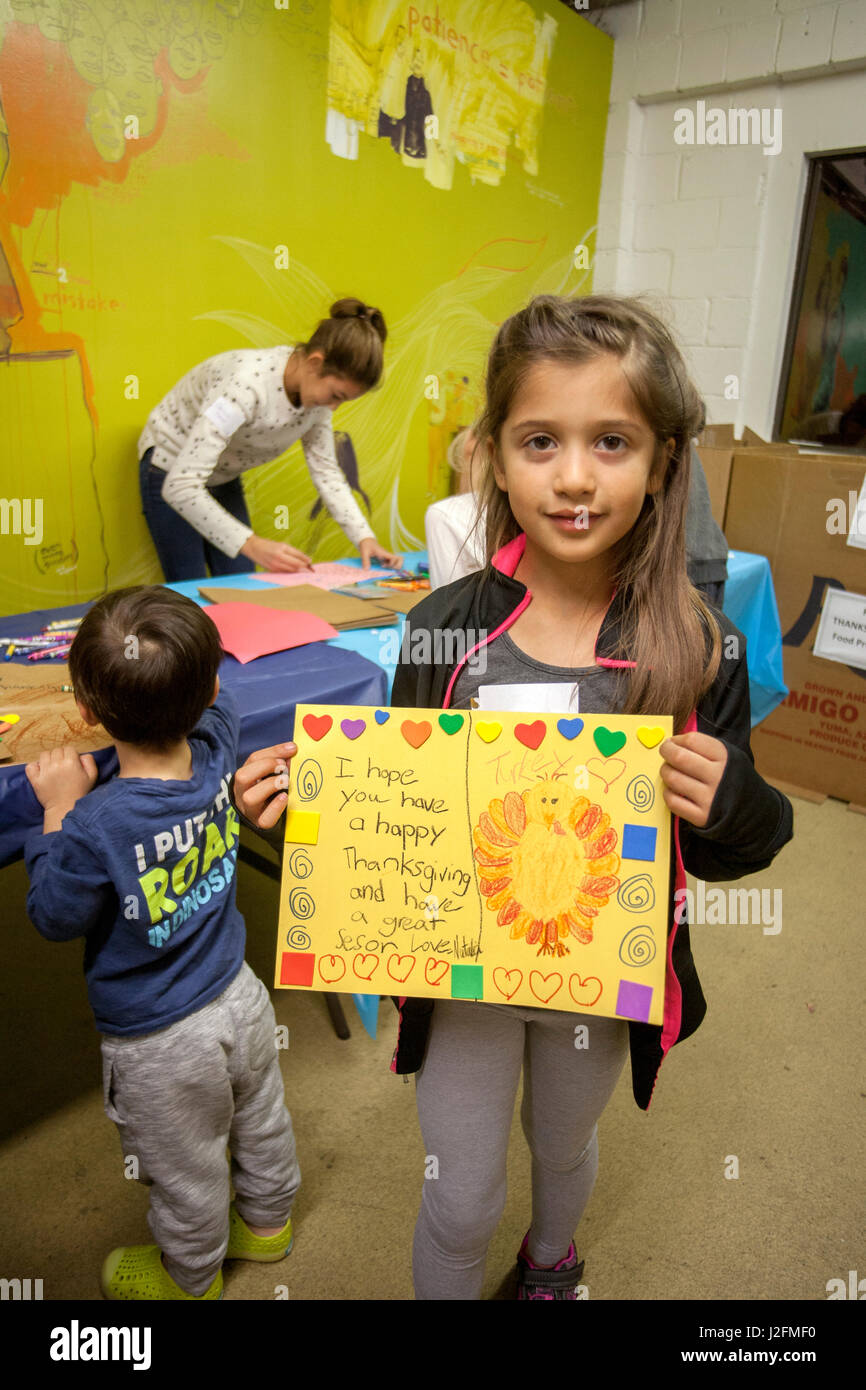 A girl volunteer at a homeless shelter in Costa Mesa, CA, shows a homemade greeting card for one of the organization's clients. Stock Photo