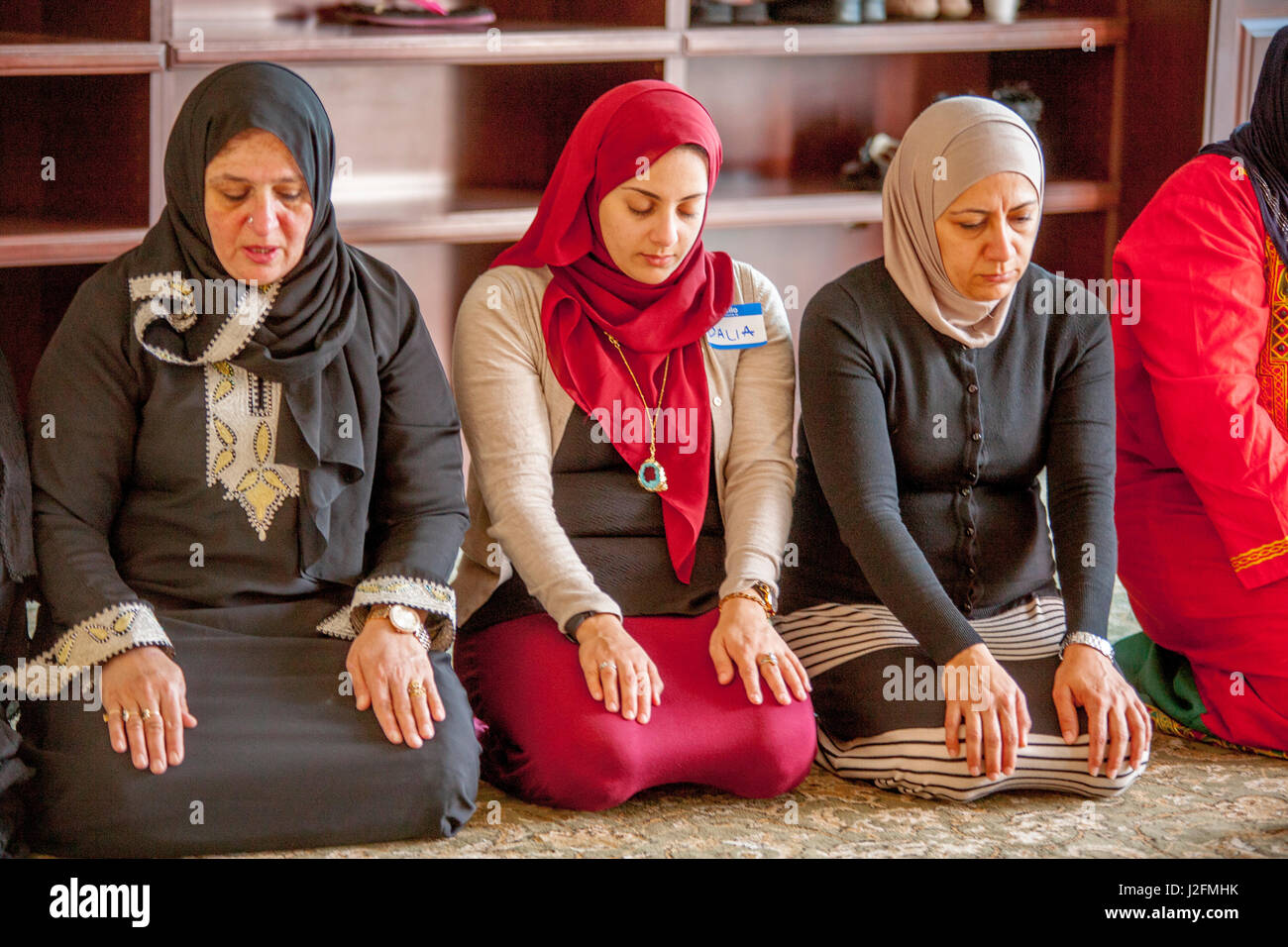 Wearing a hijabs or head scarves in a separate room, Muslim women kneel