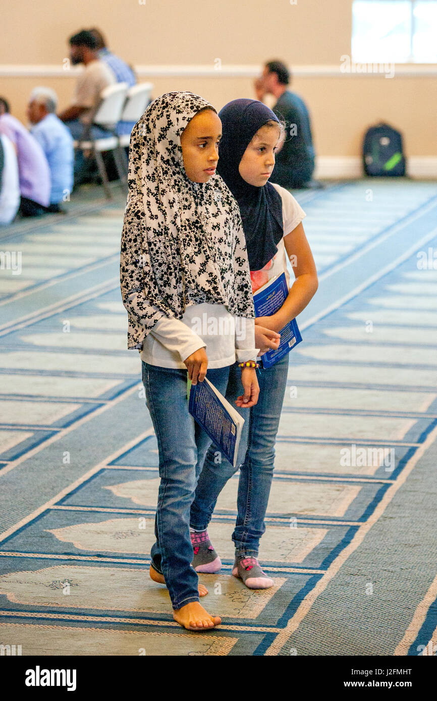 Wearing a hijabs or head scarves, two Muslim girls wait for the sermon or  Khutbah to start during religious services at an Anaheim, CA, mosque. Note  carpet with Islamic pattern and bare