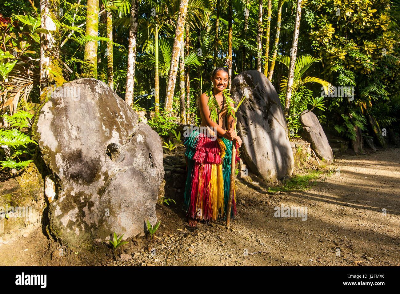 Traditional dressed girl standing before Stone money on the island of Yap, Micronesia Stock Photo