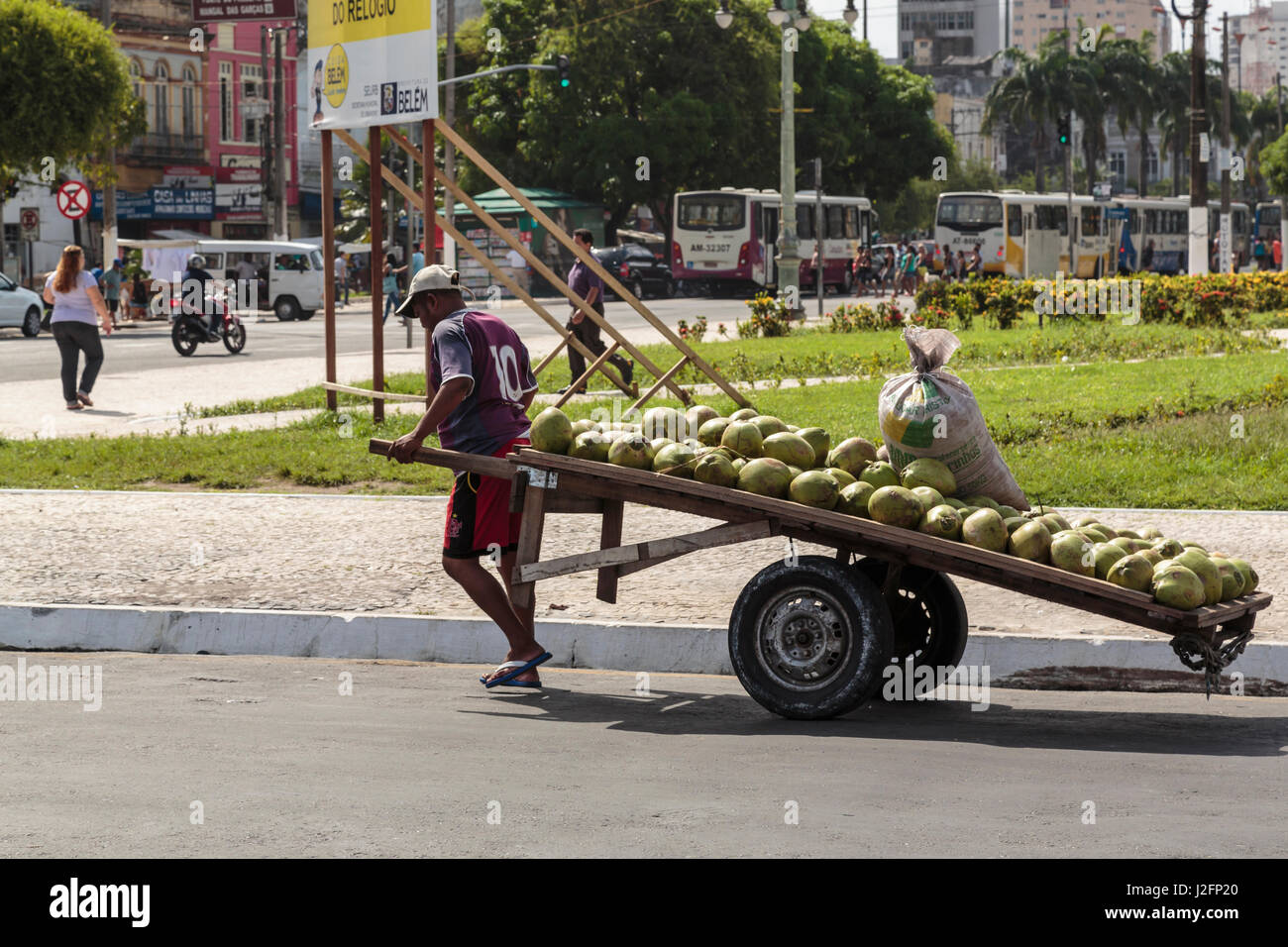 South America, Brazil, Belem. Man pulling cart of coconuts down street