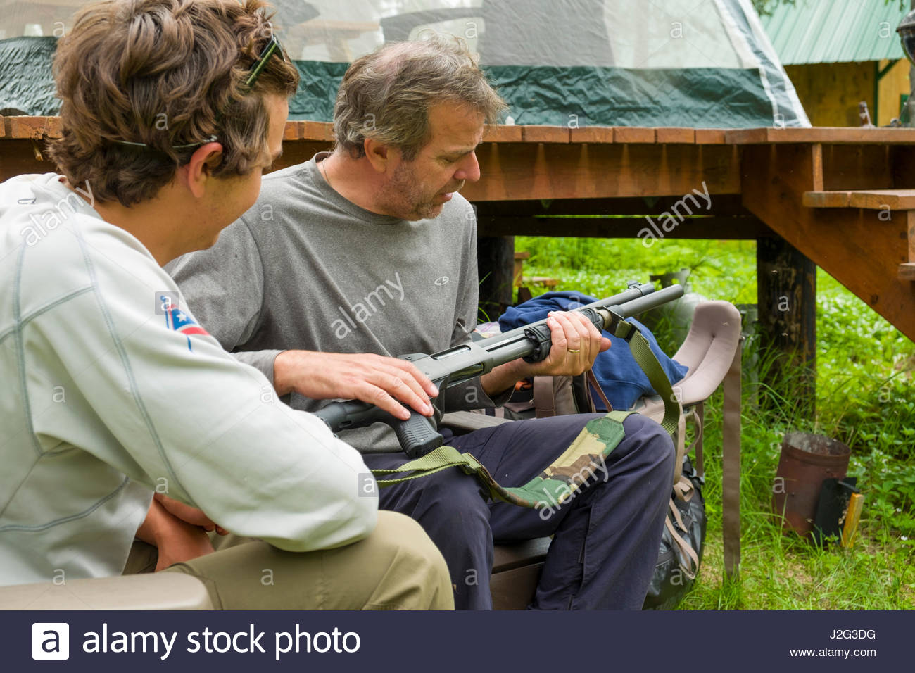 Father showing son the proper and safe operation a Remington 870 pump  shotgun at a remote
