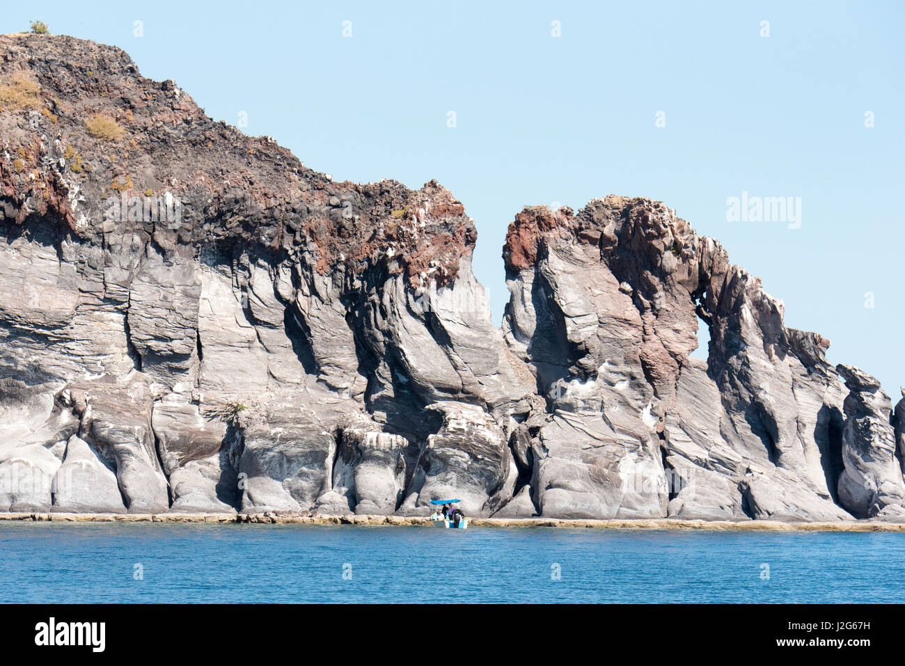 Mexico, Baja California Sur, Sea of Cortez, Loreto Bay. Isla Coronado lava formations. Panga with boaters gives sense of scale Stock Photo