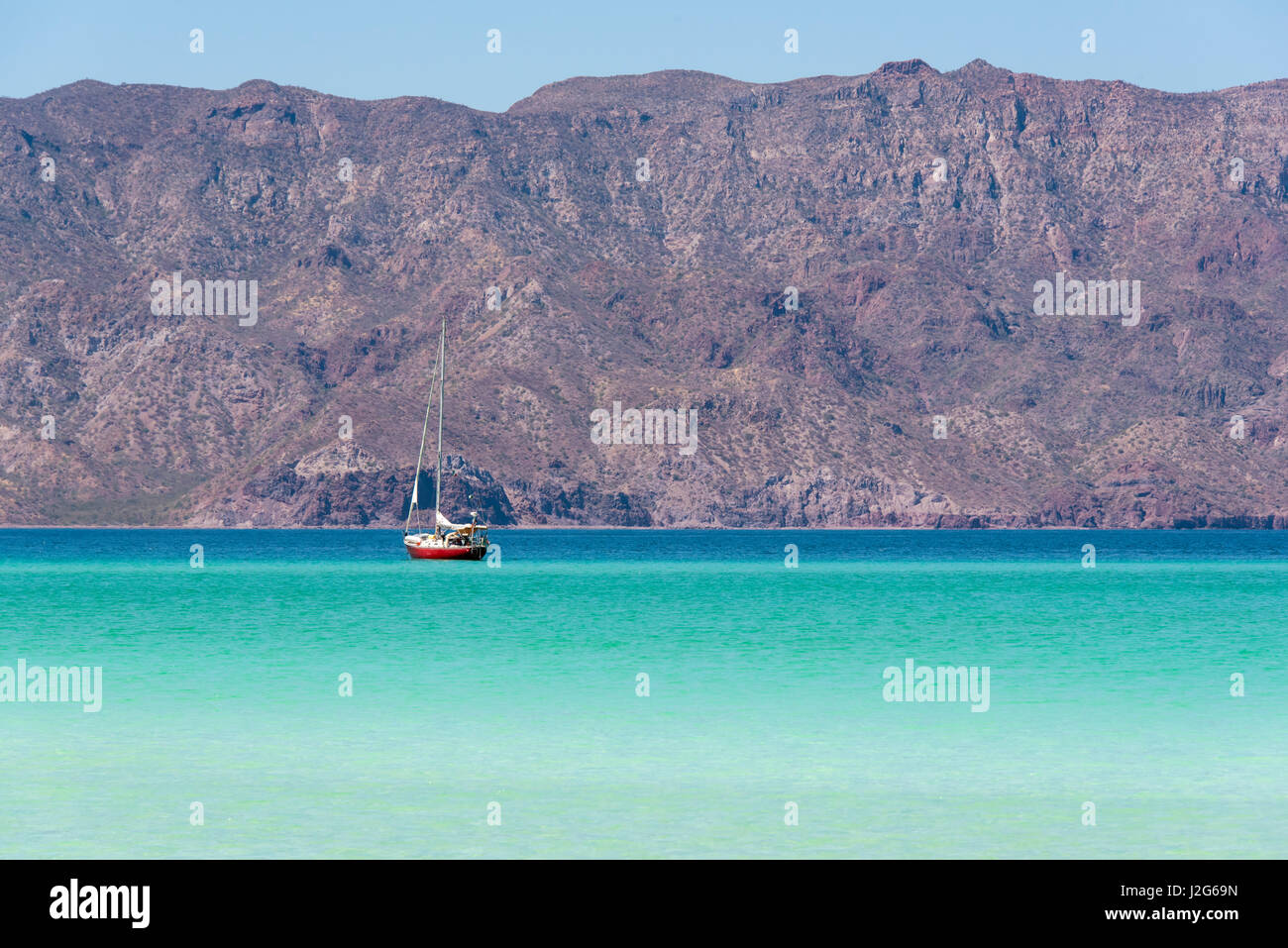 Mexico, Baja California Sur, Sea of Cortez, Loreto Bay. Lone sailboat on flat calm water with Sierra de la Giganta beyond Stock Photo