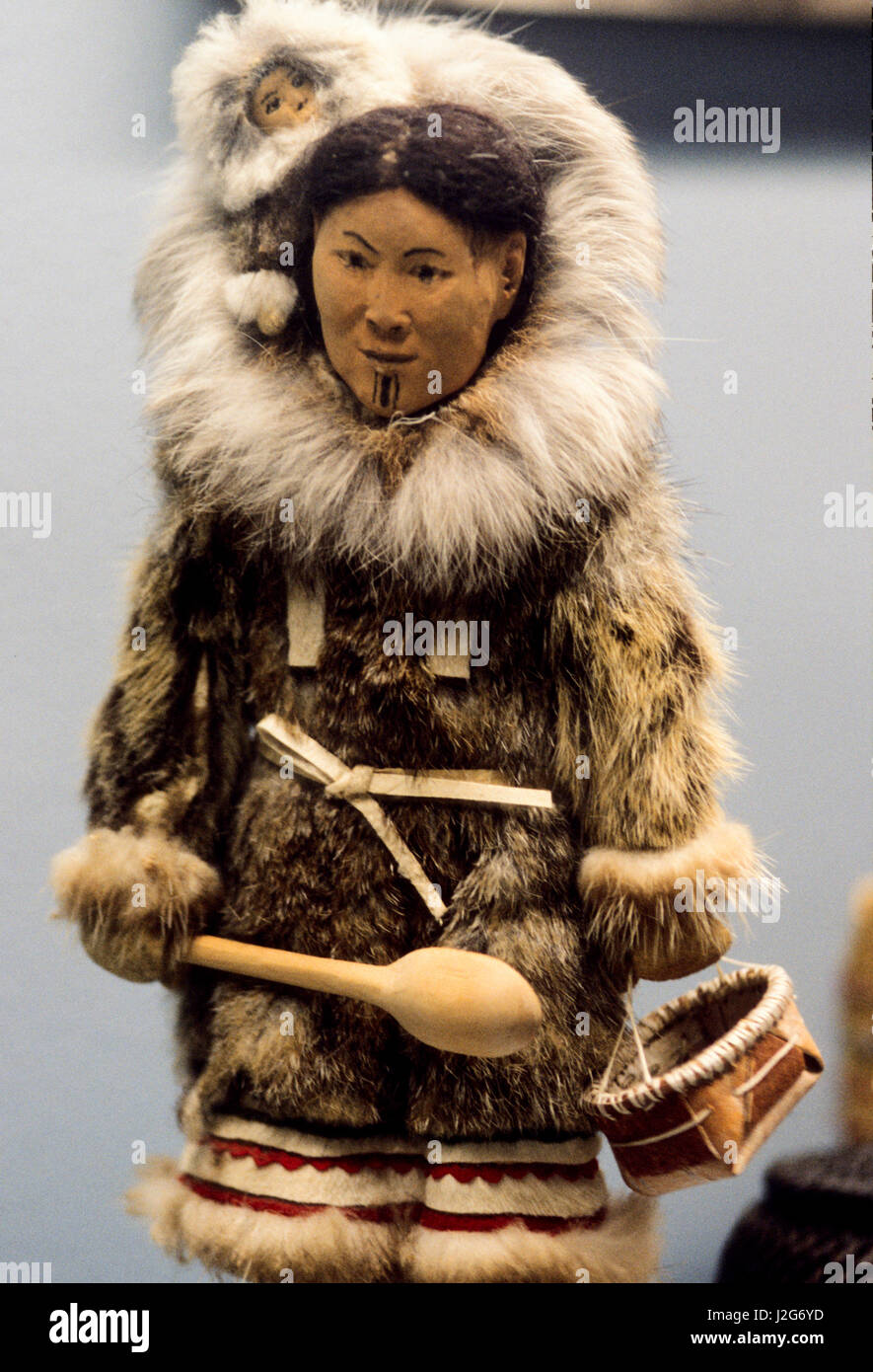 Native American artifact of an Athabaskan doll carved from wood dressed in traditional fur parka with a baby being carried inside the hood Stock Photo