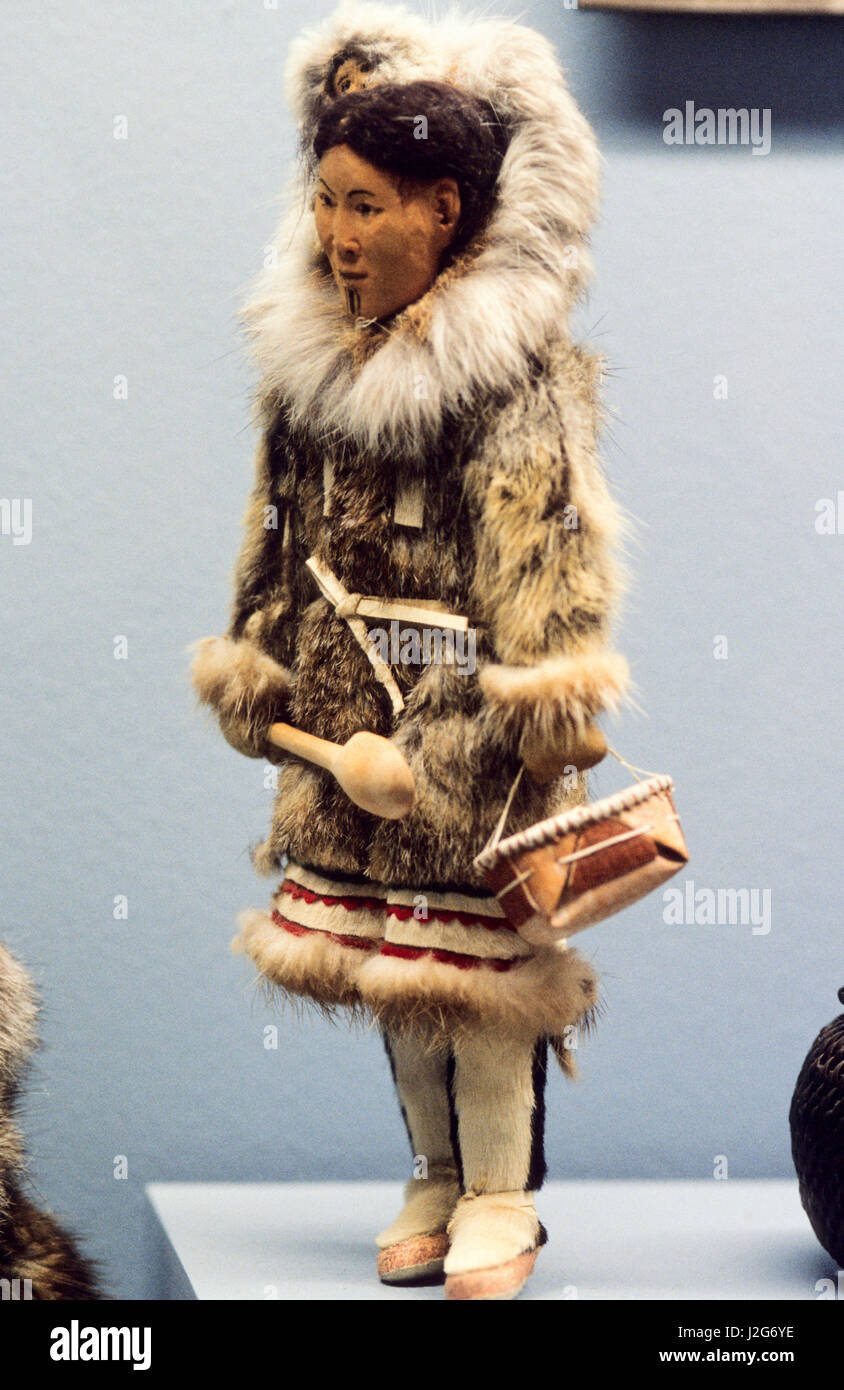 Native American artifact of an Athabaskan doll carved from wood dressed in traditional fur parka with a baby being carried inside the hood Stock Photo