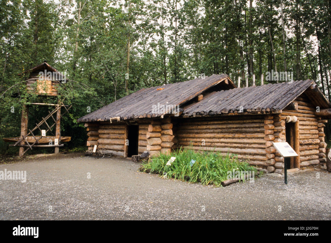Traditional Athabaskan village of a log constructed shelter and a tall