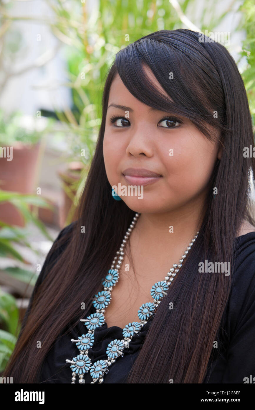 Close-up of young Navajo woman's face, she is wearing traditional turquoise squash blossom necklace and bracelet. (MR) Stock Photo