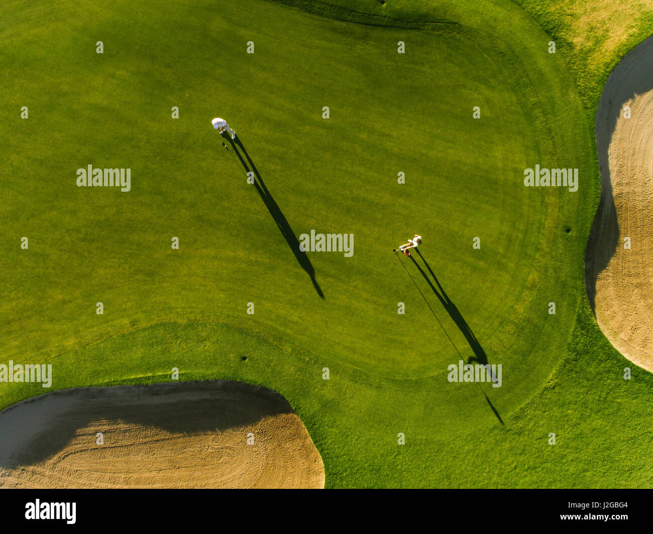 Aerial view of professional golfers playing on putting green on a summer day. Players on a green golf course. Stock Photo