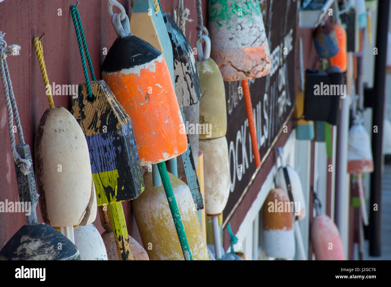 Maine, Bar Harbor. Colorful lobster trap buoys hanging on wall. Stock Photo