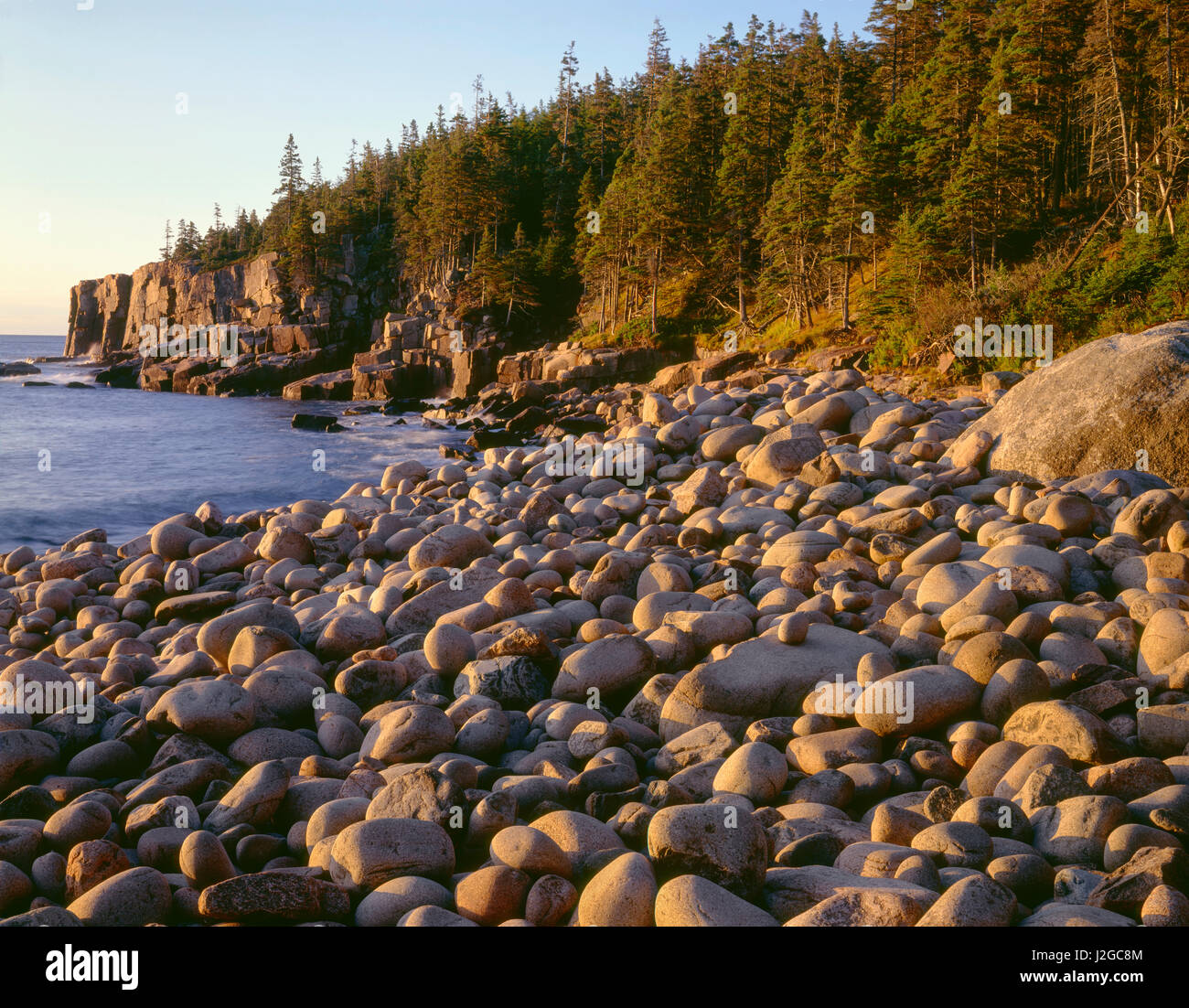 USA, Maine, Acadia National Park, Sunrise light on wave-rounded rocks ...