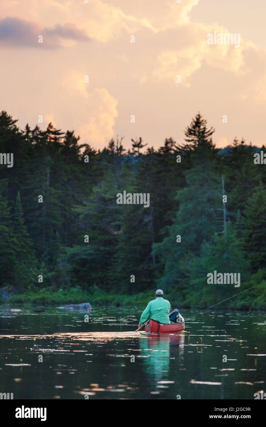 A man flyfishing on Little Berry Pond in Maine's Northern Forest. Cold